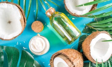 Óleo de coco engarrafado com frutos de coco ao lado
